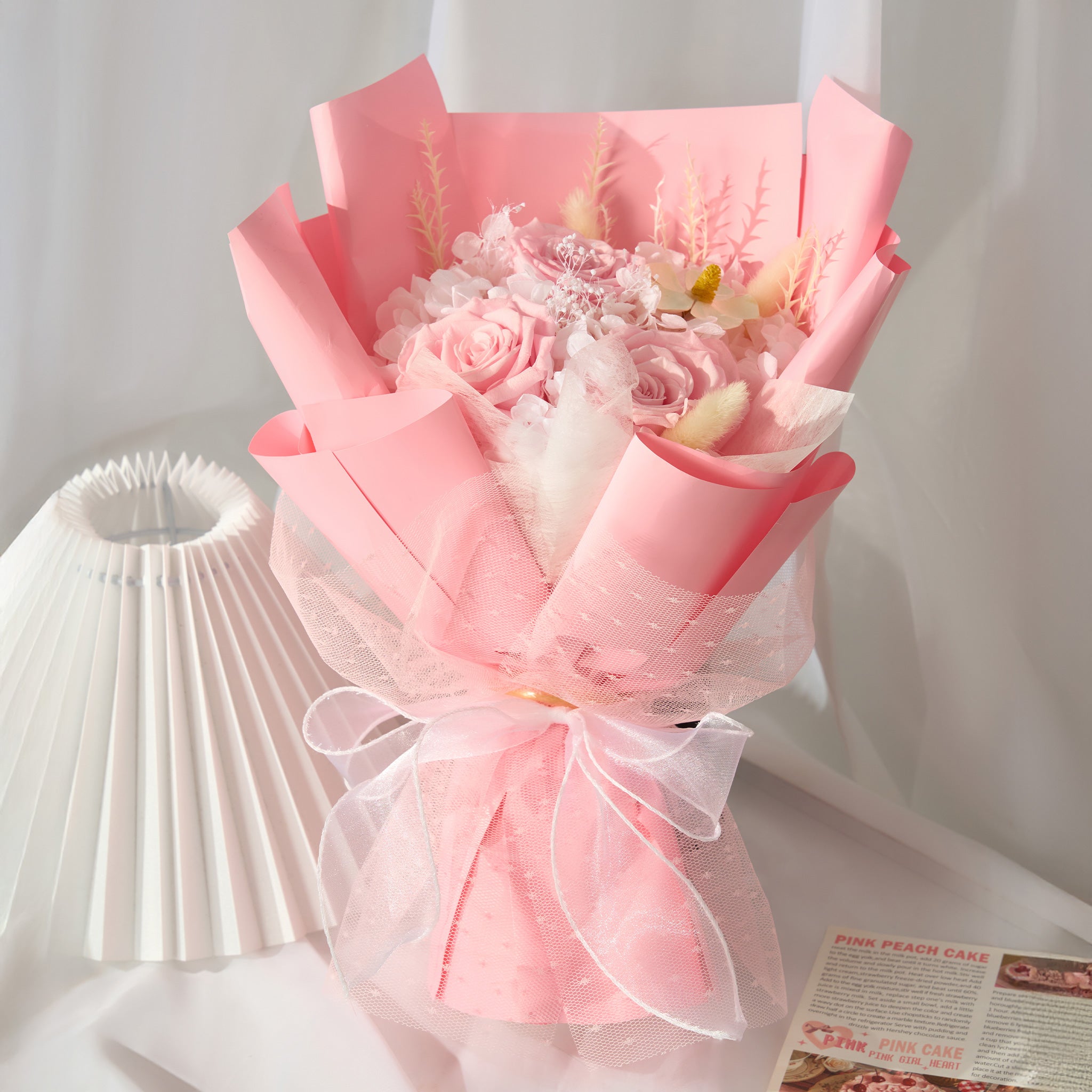 Bouquet of flowers wrapped in pink paper with a white bow on a light background