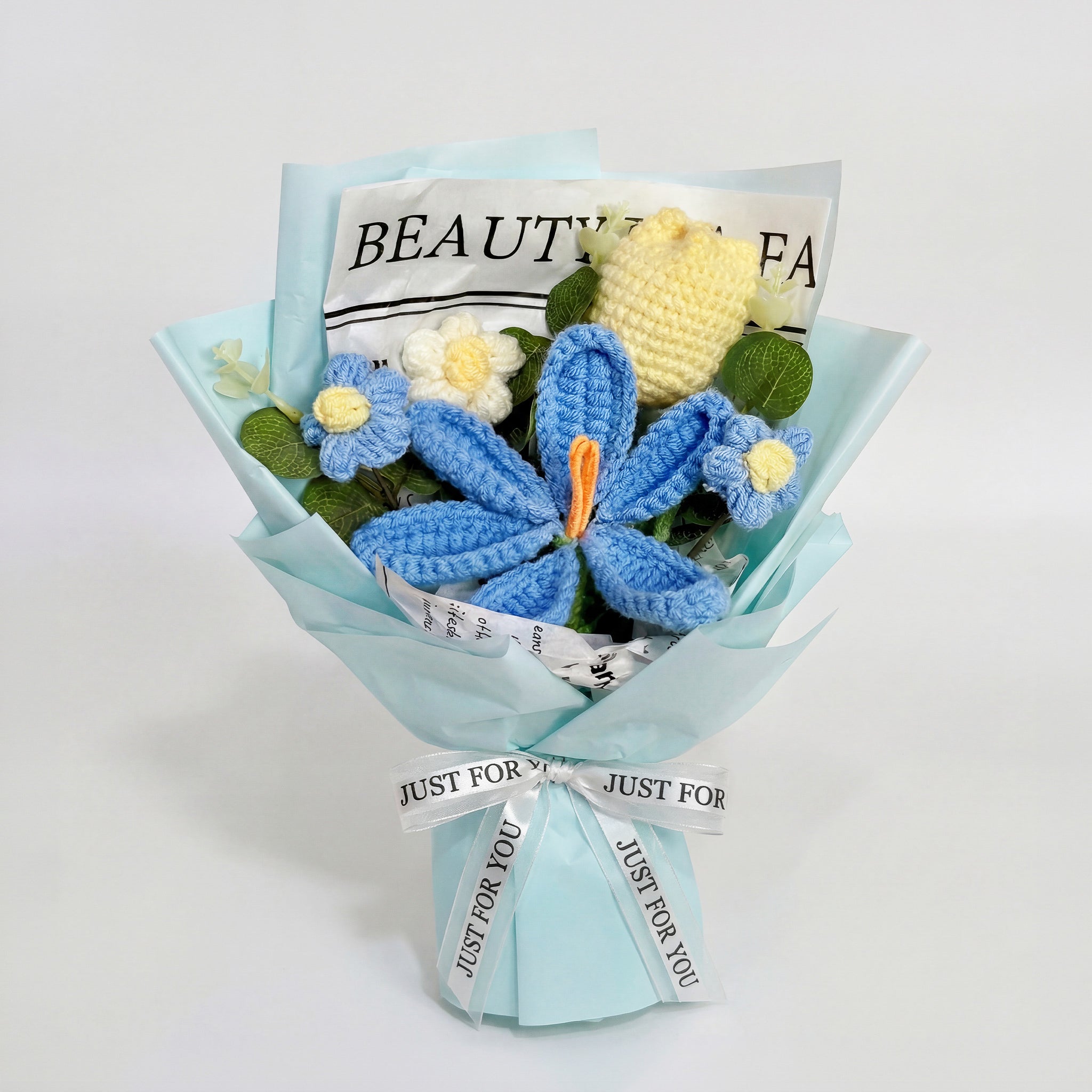 Bouquet of knitted flowers with a blue wrap and 'Just for You' ribbon on a white background