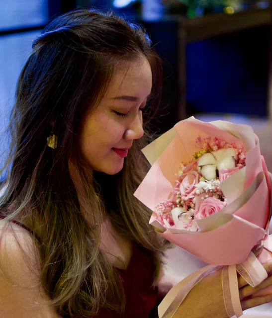 Woman smiling while holding a bouquet of pink flowers, perfect for celebrating special occasions