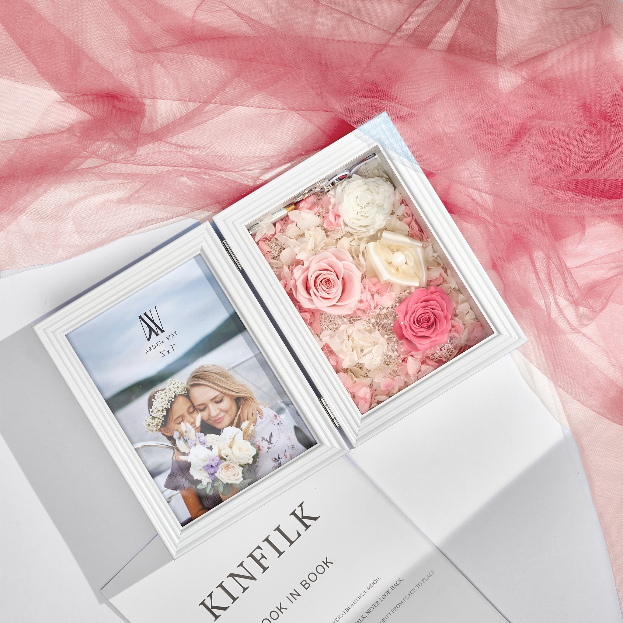 Album with a photo of two people and a compartment filled with preserved flowers on a pink fabric background